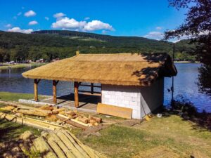 Nádtetős hűsölő pavilon vízparti környezetben, nyári hűvös klímával